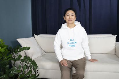Asian woman wearing a hoodie sitting on the couch