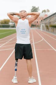 Man with a prosthetic leg wearing a tank top on the running track - back view
